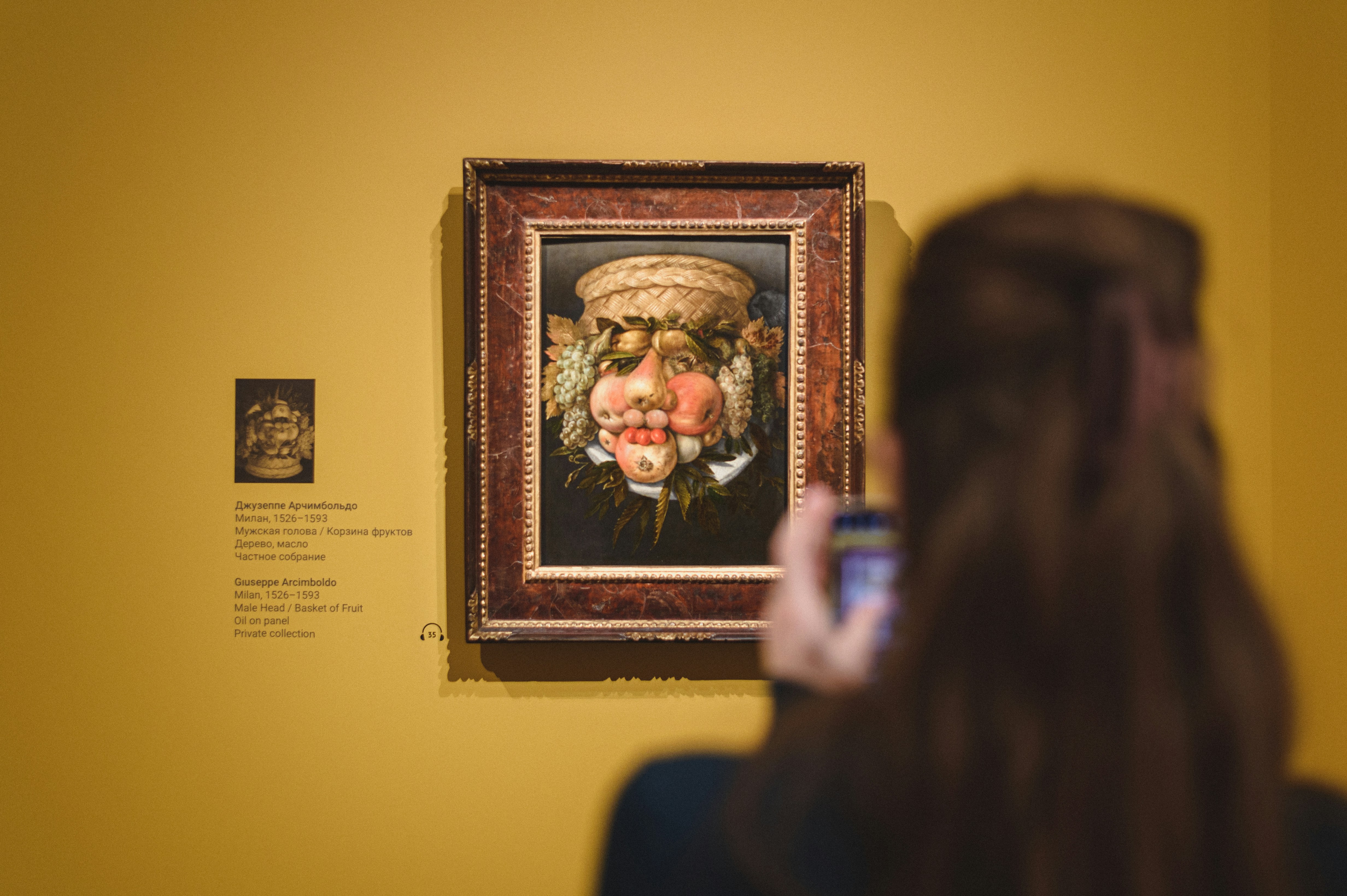 A girl takes a picture of a Baroque painting with her phone.